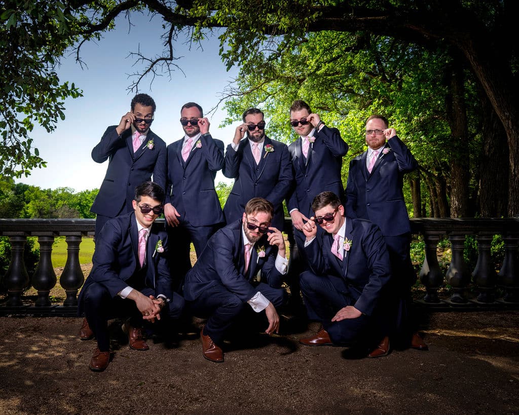 Groomsmen pose for photo under a tree.
