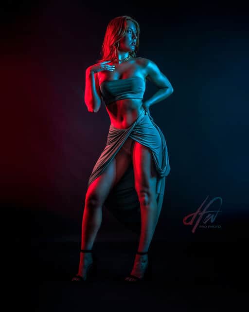 Model posing in red and blue gelled lighting,