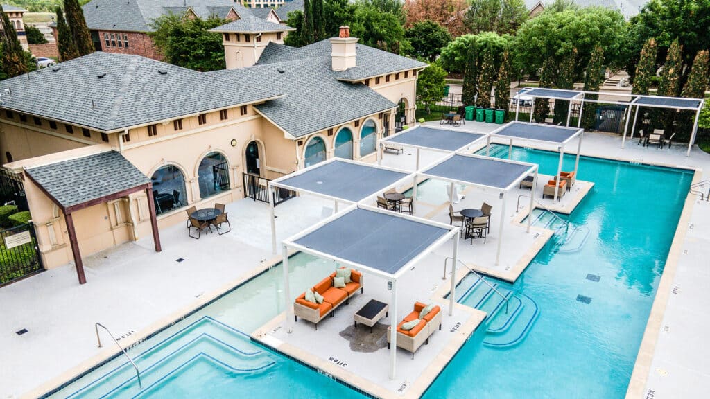 Birds Eye view of pool behind a large house.