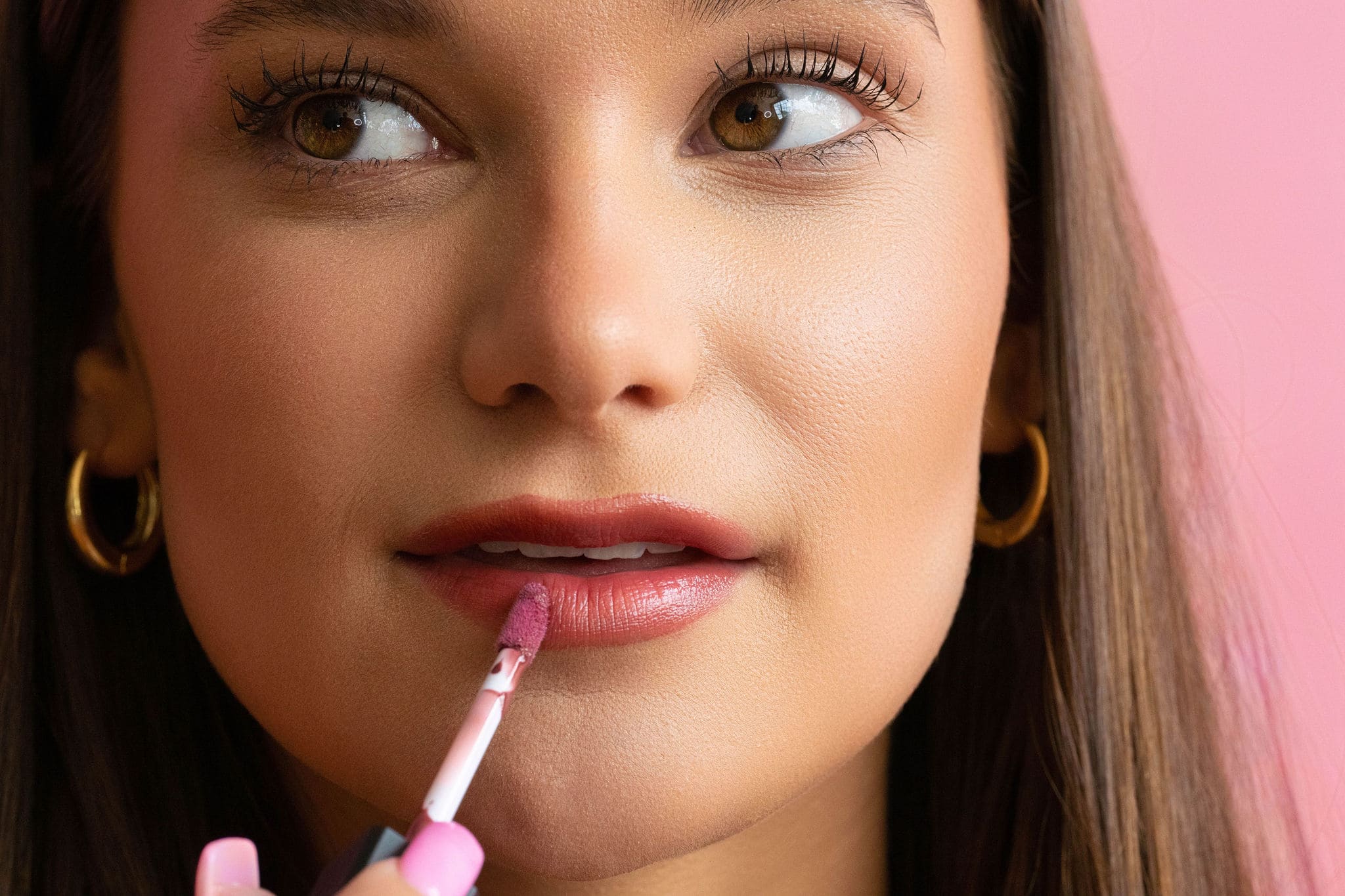 Woman apply lip gloss.