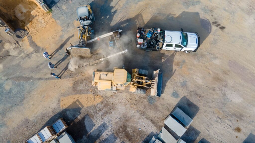 Top down view of truck being loaded by front-end loader at a stone supply yard.