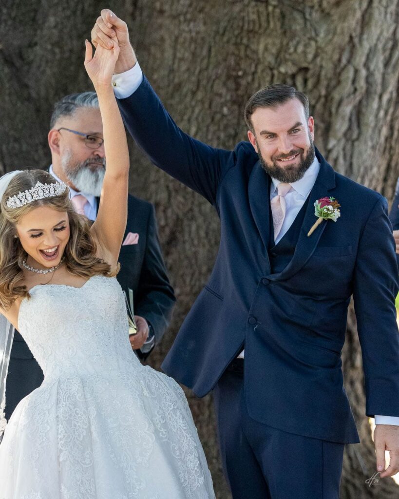Couple holding hands with arms up after wedding ceremony.
