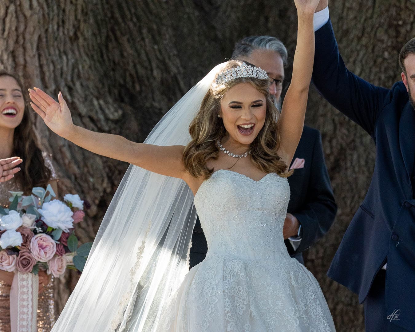 Happy bride with smile and arms up in celebration after ceremony.