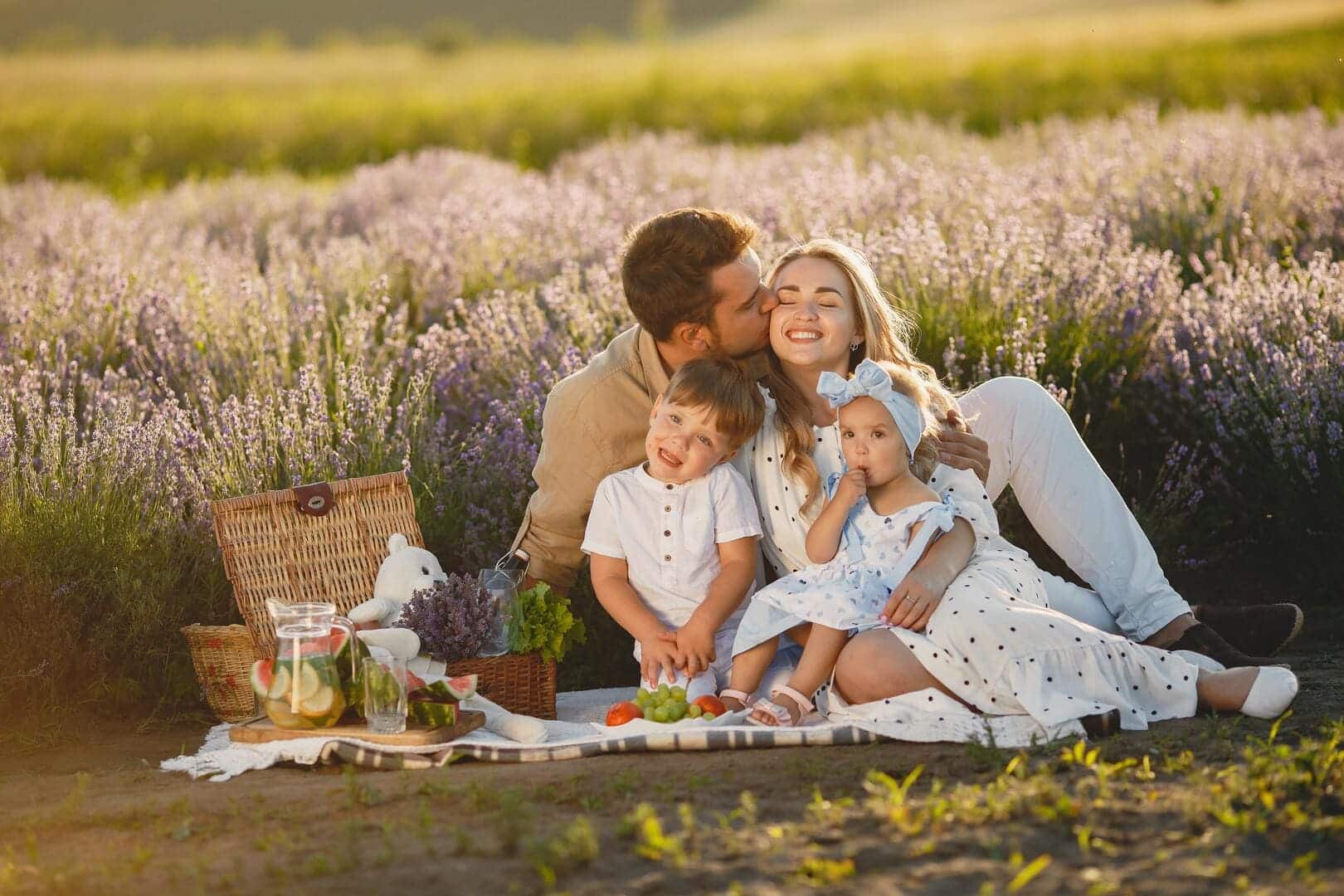 Family on picnic blanket with flowers in the background.